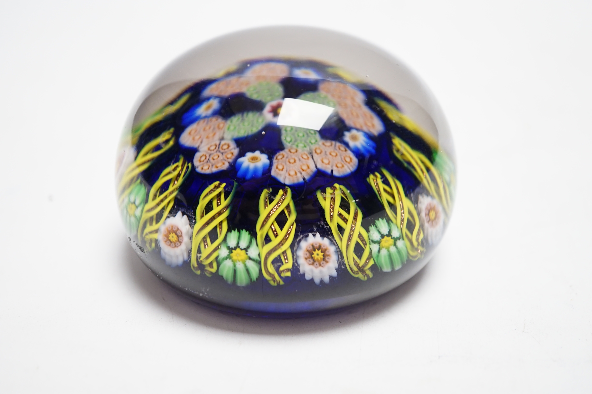 A Paul Ysart millefiori glass paperweight, pre-war Moncrieff period, with central complex canes within a border of aventurine and latticino spokes, transparent blue ground, rough pontil, 7.5cm